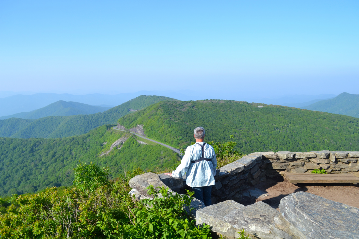 A hiker takes in the mountain view from the Craggy Pinnacle Trail